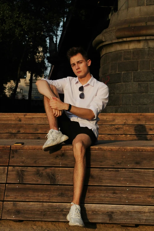 a man in shorts and shirt sitting on a bench