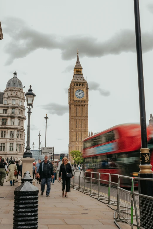 a clock tower and people walking down the sidewalk