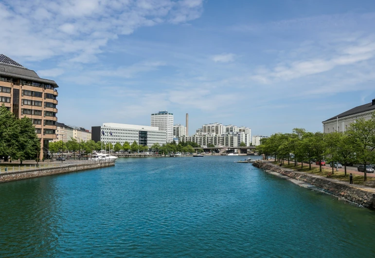 a river with many trees lining it is next to buildings