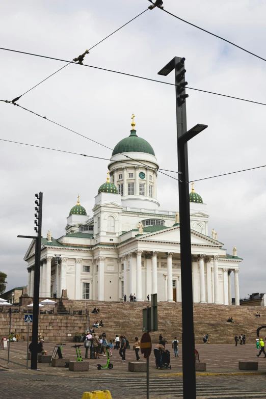 a tall white church with many people walking around