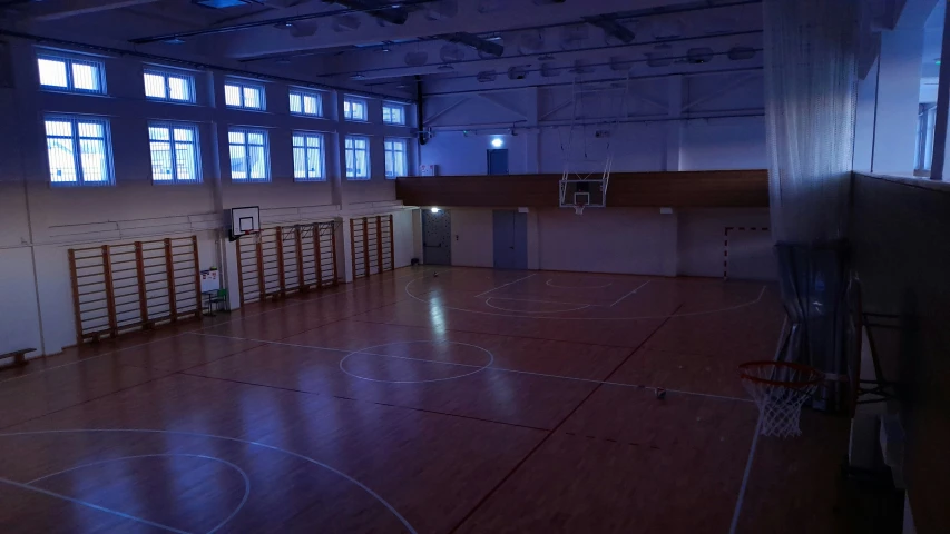 an empty gym with basketball hoop, lights and floor