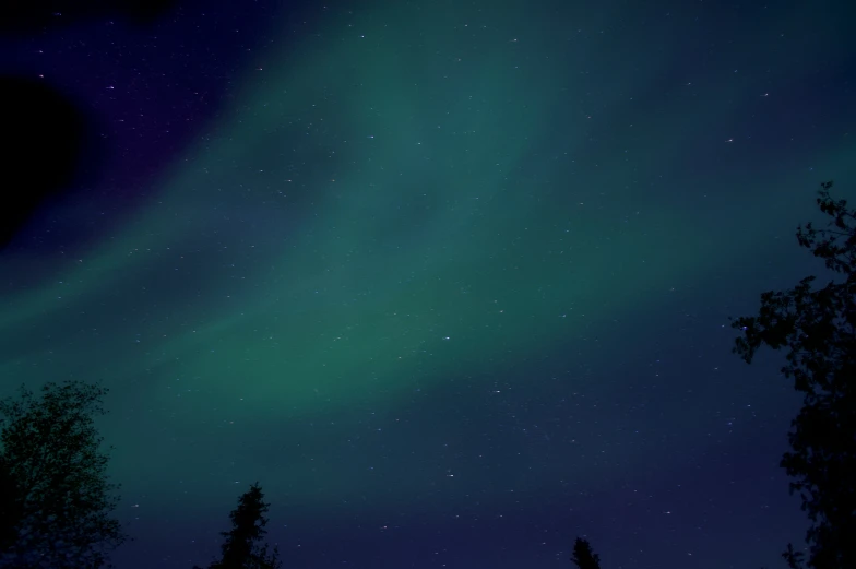 a night sky with a large green aurora and a blue sky