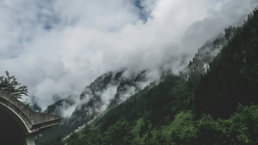 a view of a mountain next to a bridge under a cloudy sky
