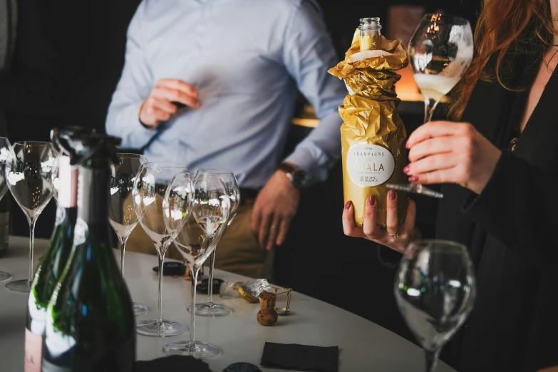 a lady holding up some wine glasses with the guy behind her