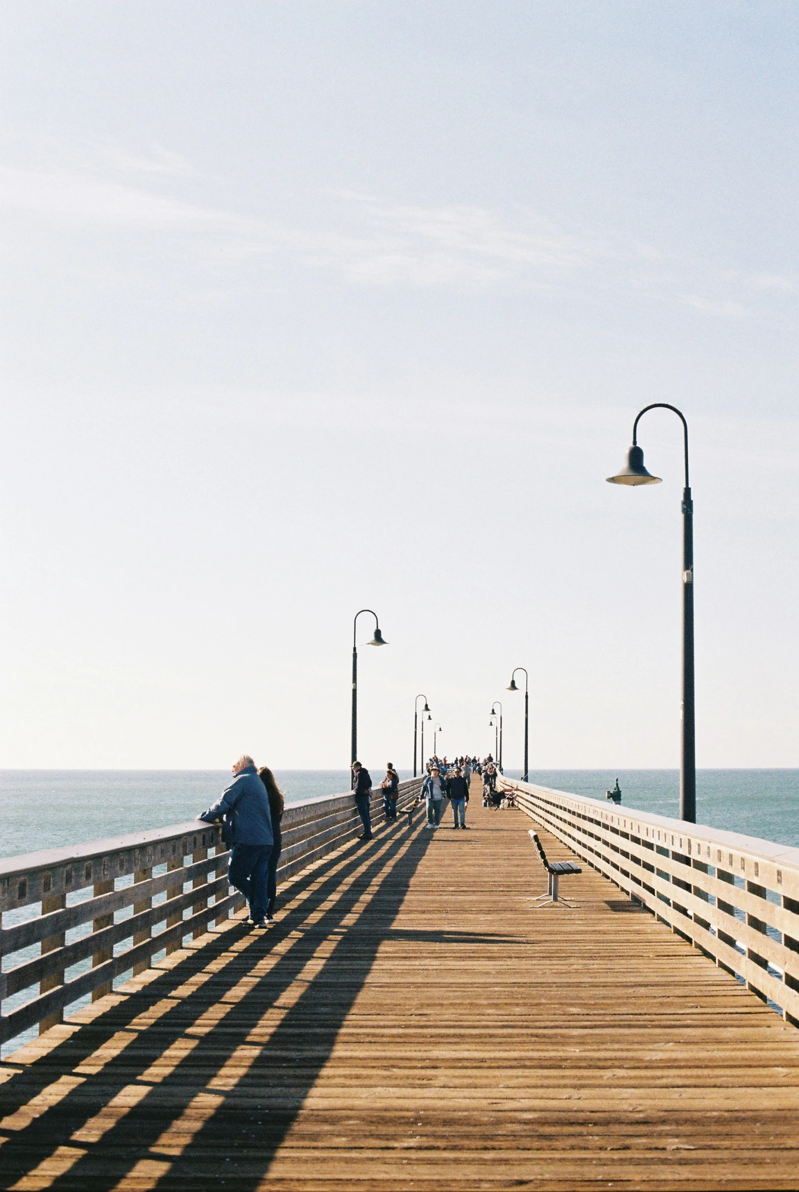 people walking on a wooden pier in front of the ocean