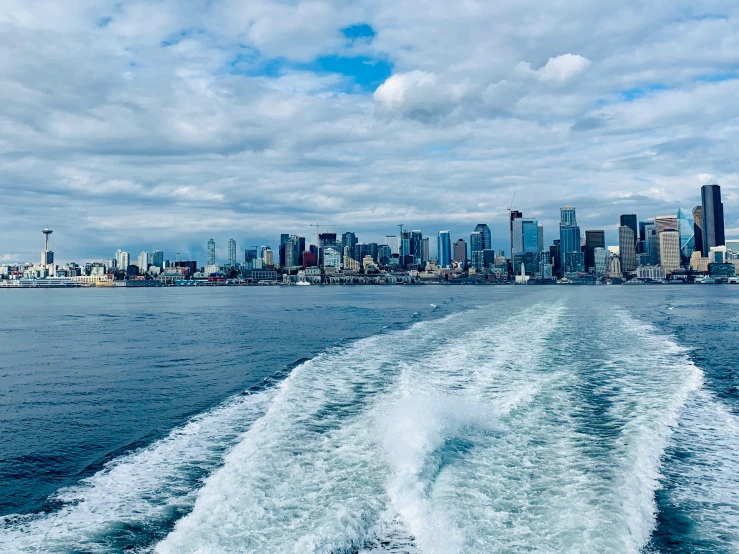 a boat wakers behind the head of a city with skyscrs