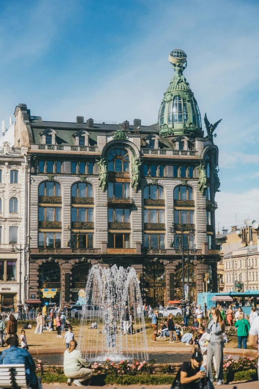 people walk around a city park in front of a large building