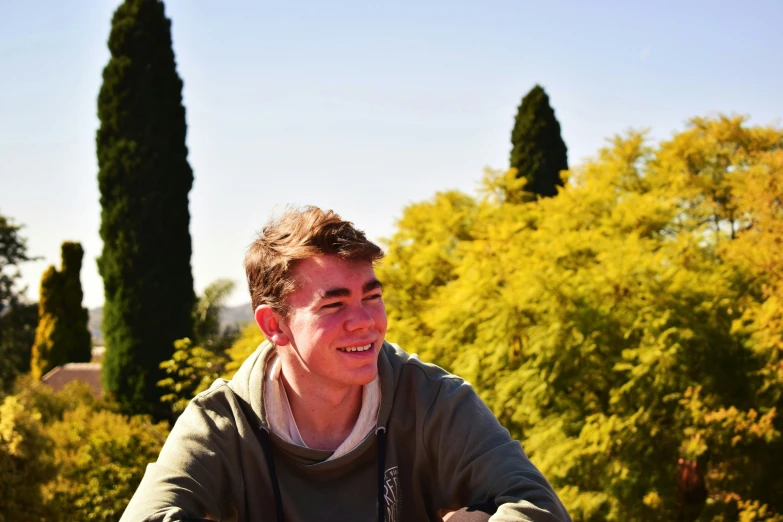 man standing in front of a row of trees smiling