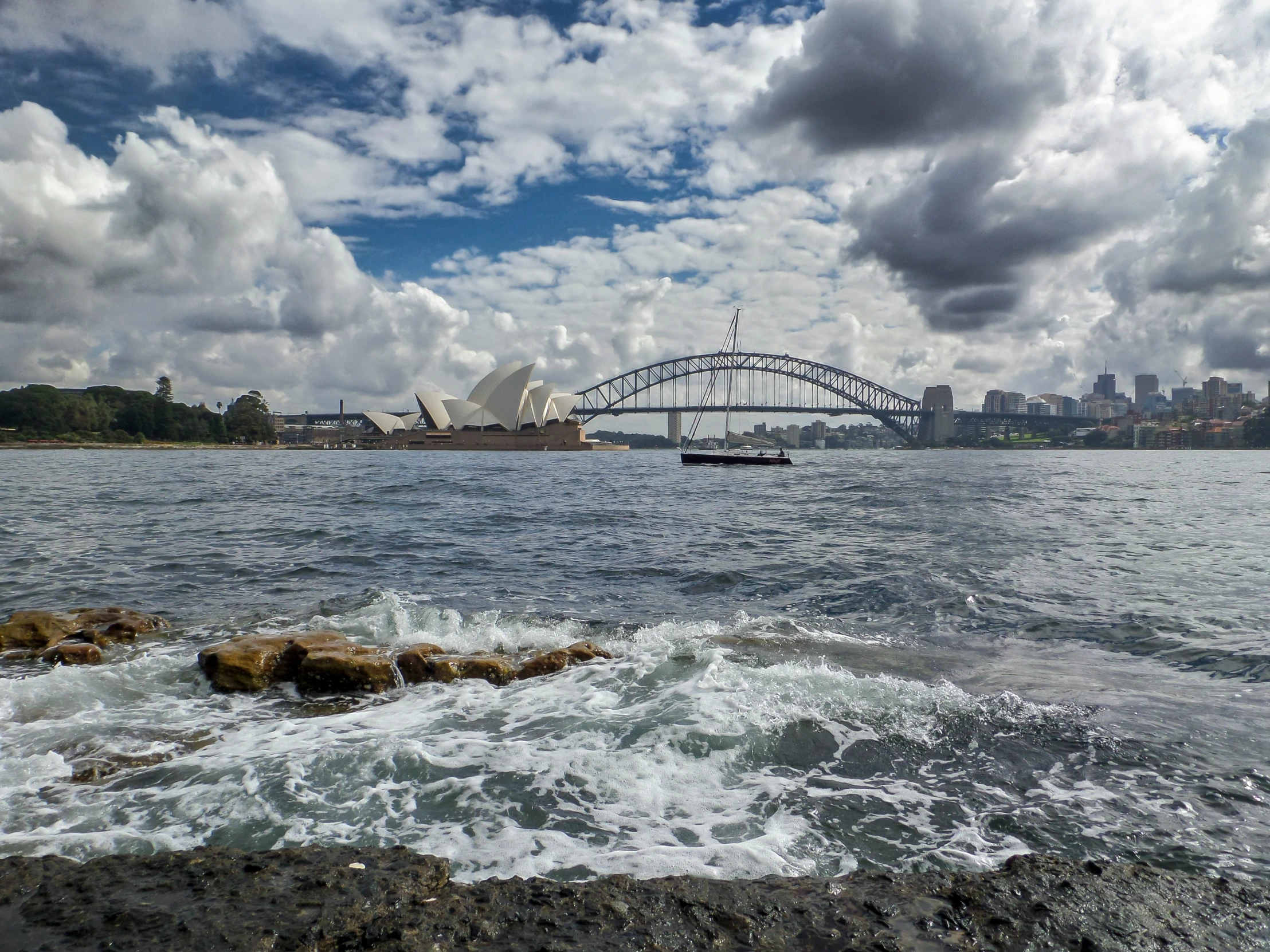 view from the shore of the ocean with a bridge over the water