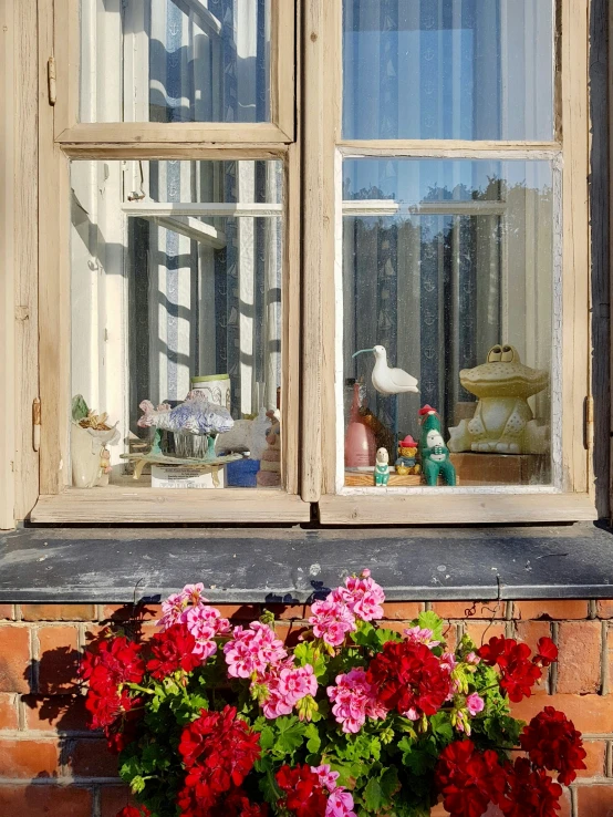 a window that has flowers and a bird on the window sill