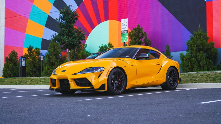 a very nice yellow sports car sitting next to the building