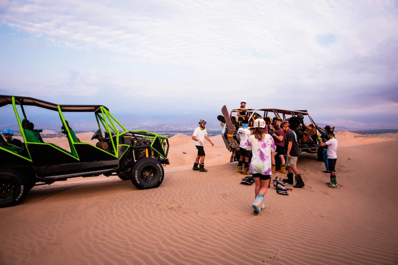 group of people at a dune buggy with cars parked in front