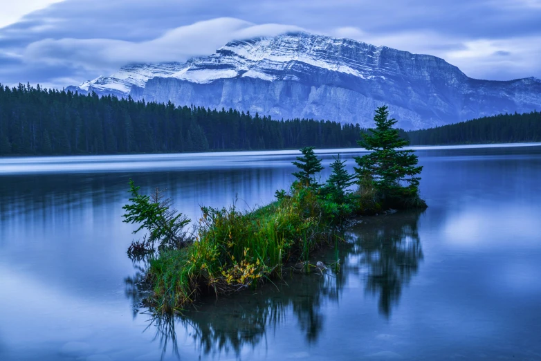 the view of a mountain peak and some water near trees