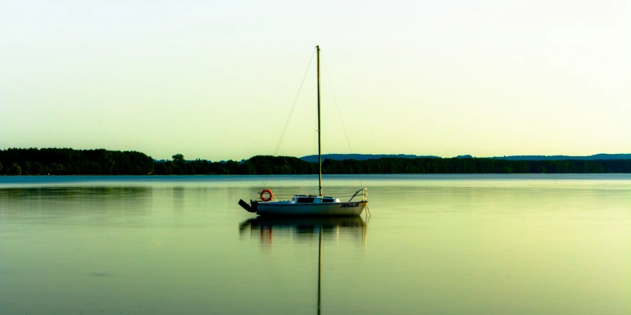 small sailboat in the middle of a lake at sunset