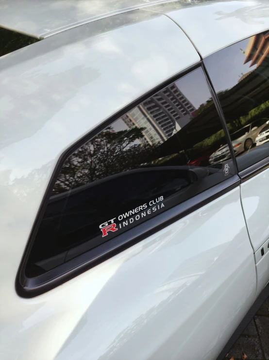 the rear window of a white car with a sticker on it