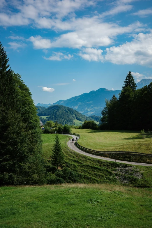 a scenic view of the mountains, green fields and a winding road