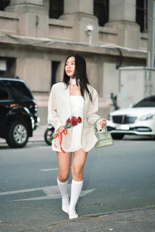 a woman in white sweater dress standing on street next to cars