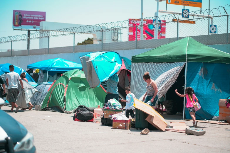 several tents with children standing inside by a wall