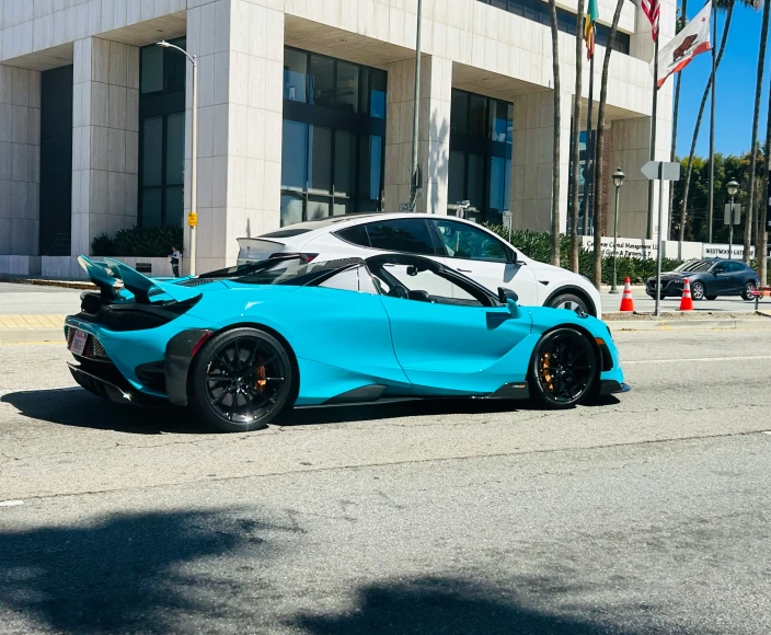 the rear end of a blue sports car on a road