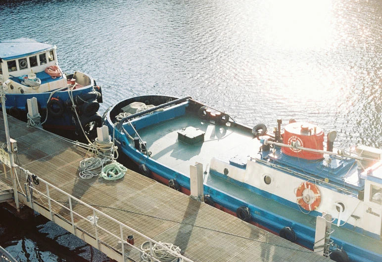 a blue and white tug boat tied up to the pier