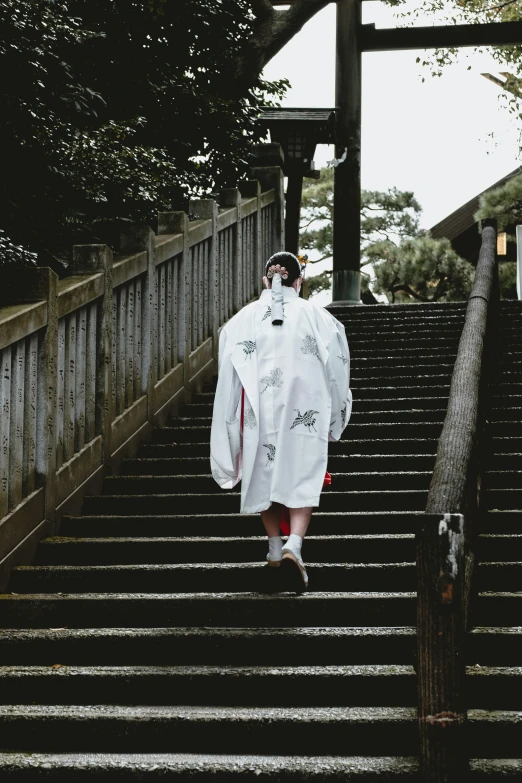 person in white robe and hat walking up stairs