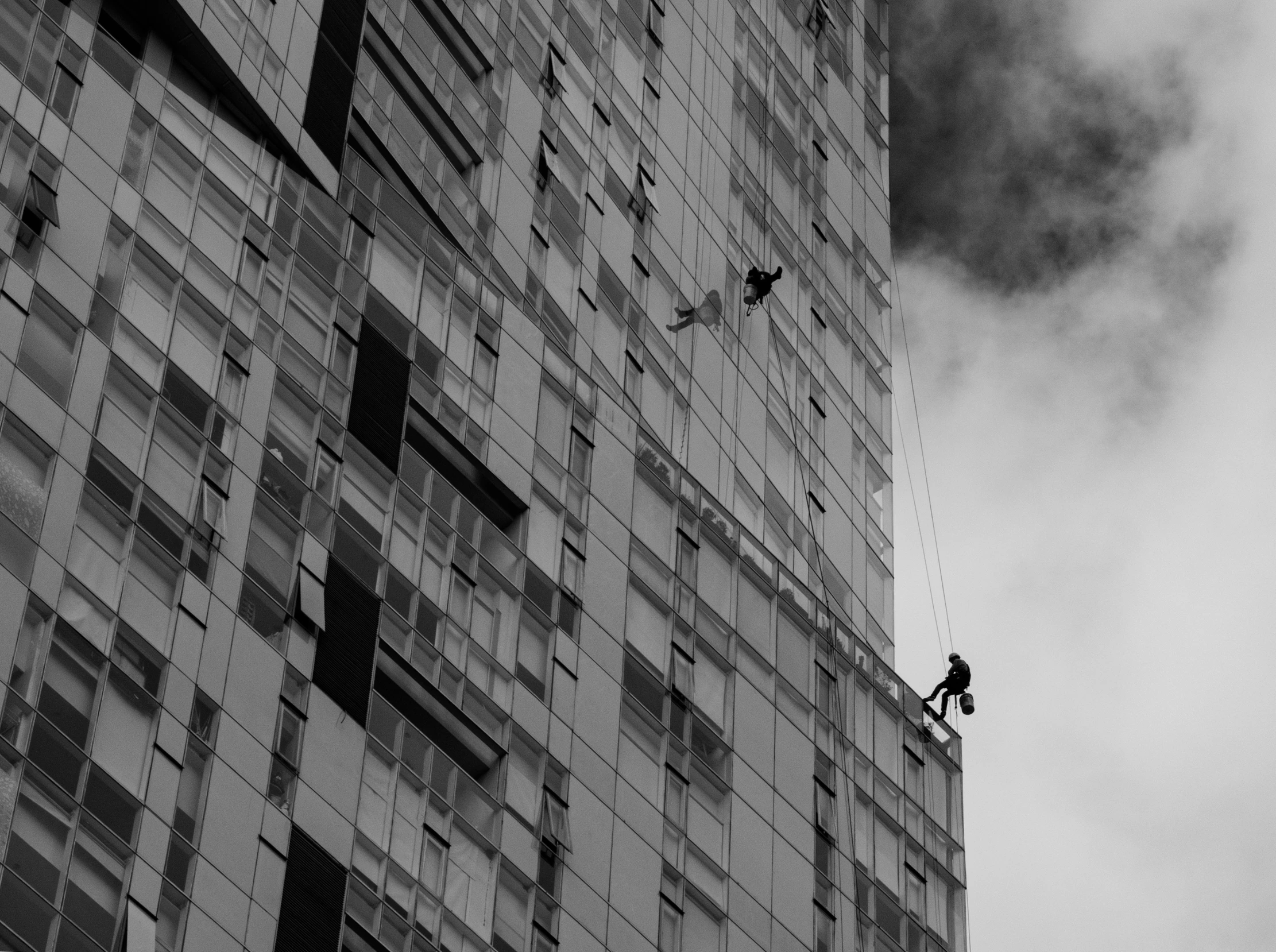 two men climbing up a wall while someone on a crane