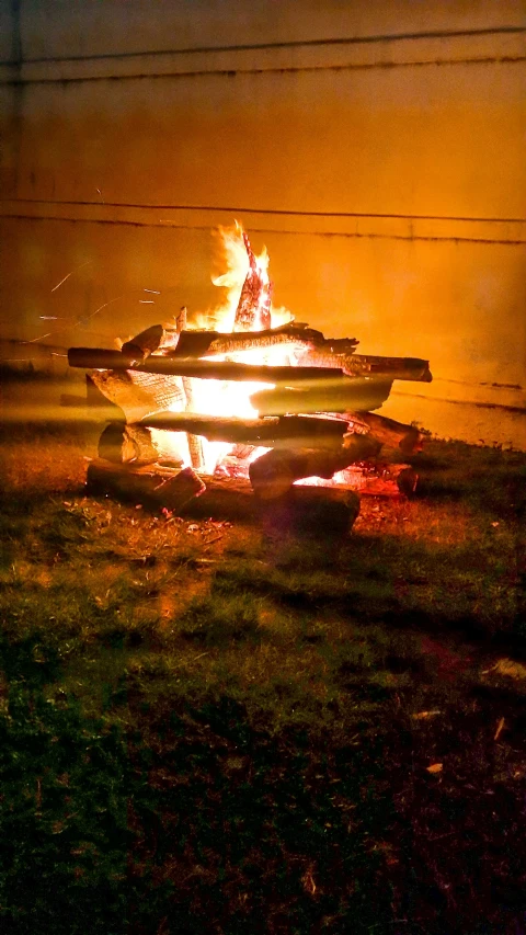 a large fire burning next to a pile of logs