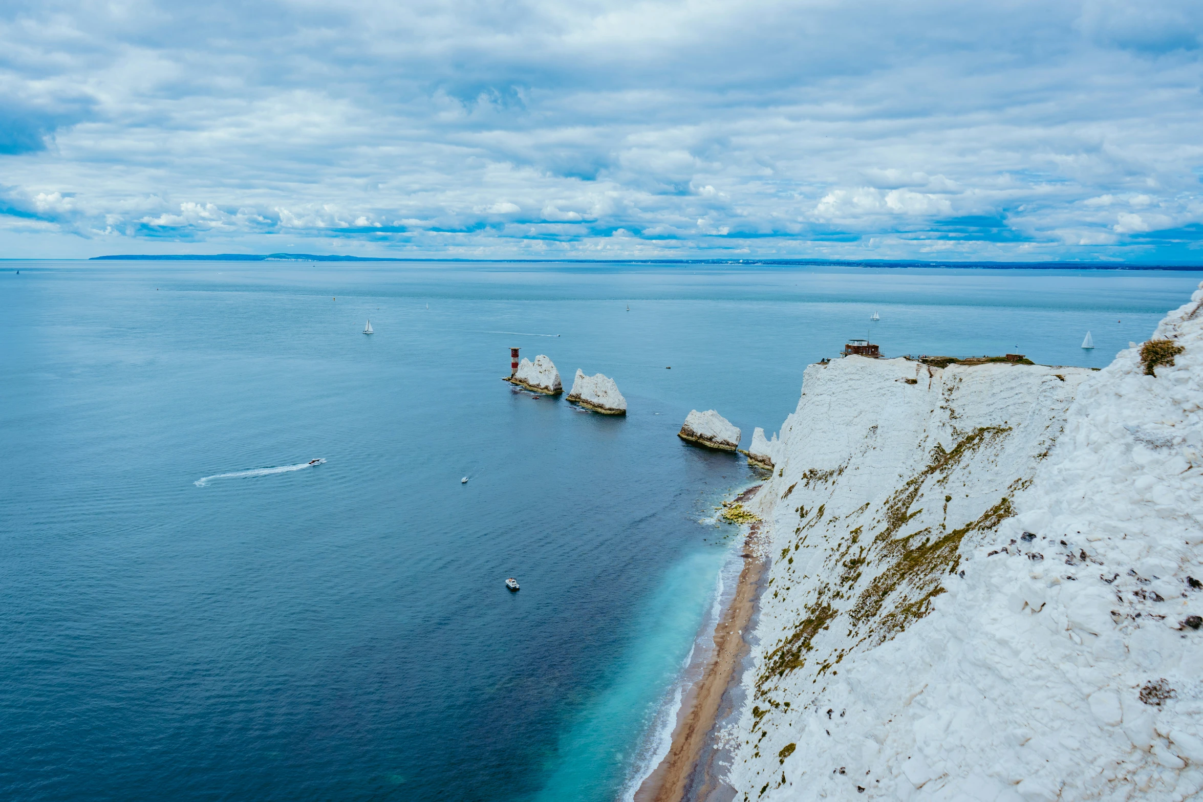 a rocky outcropping extends into the sea below a blue cloudy sky