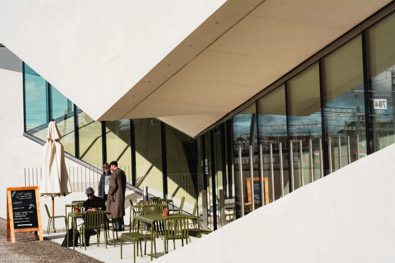 people sitting on chairs at tables under an awning