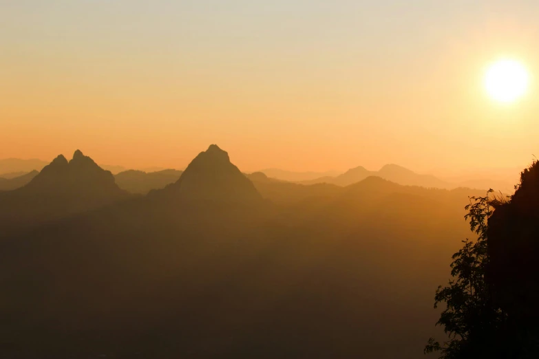 a very tall mountain in the sunset with a sun up