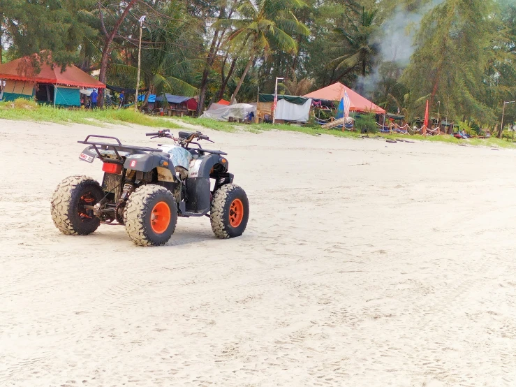 an atv is parked on some sand by a field