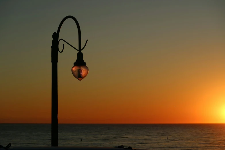 a lamp is on an ocean front and a person is walking