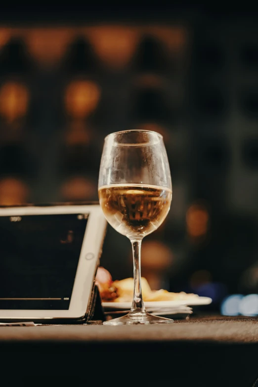 a glass of wine and tablet on a table