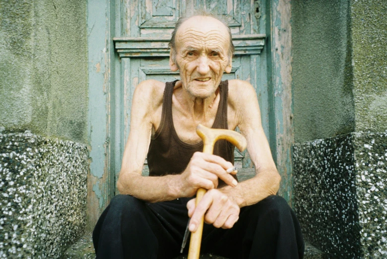 an old man sits on the steps holding a cane