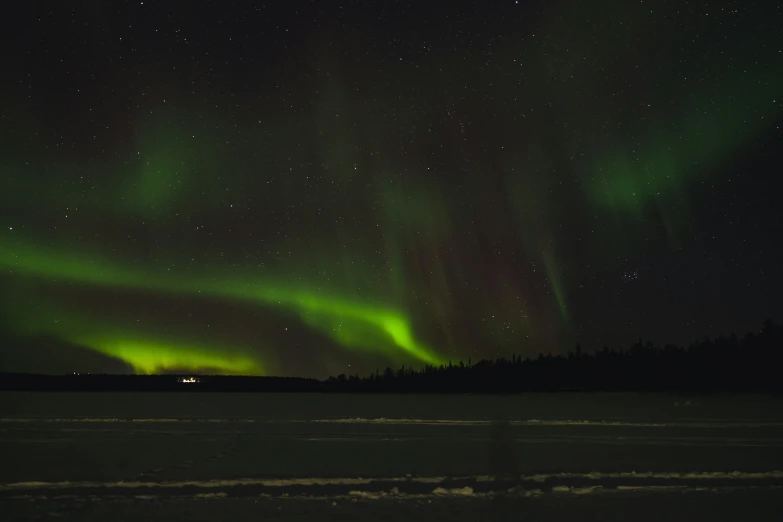 a view of green aurora lights over snow covered ground