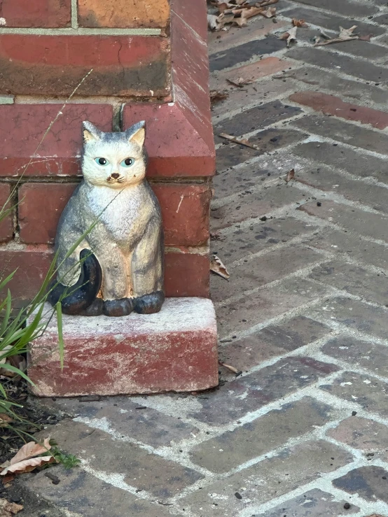 a statue on a brick wall that is sitting on the ground