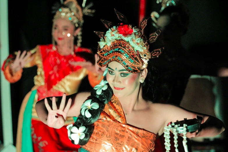 a dancer wears an orange top with decorations on her head