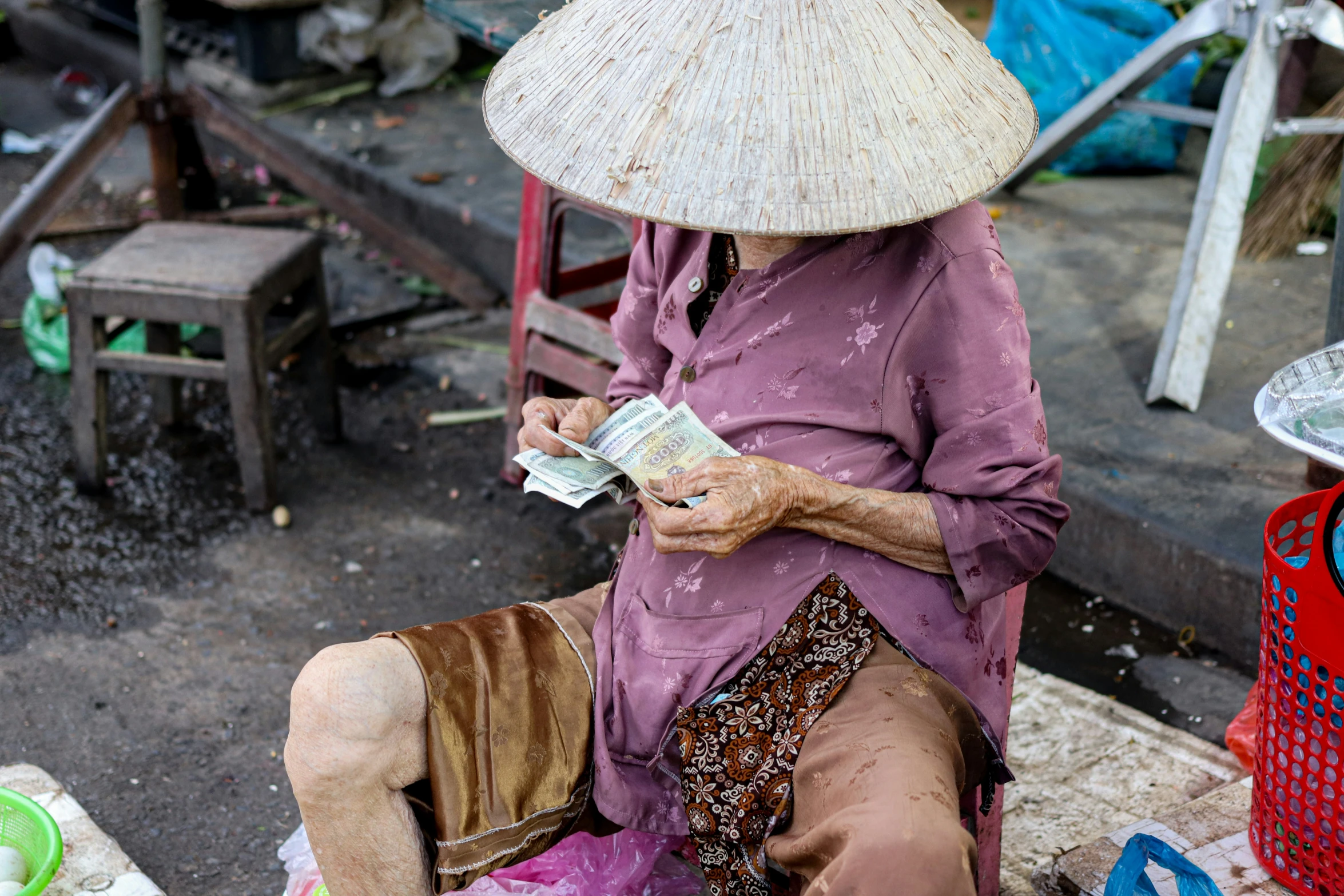 woman in a straw hat is sitting on a bench