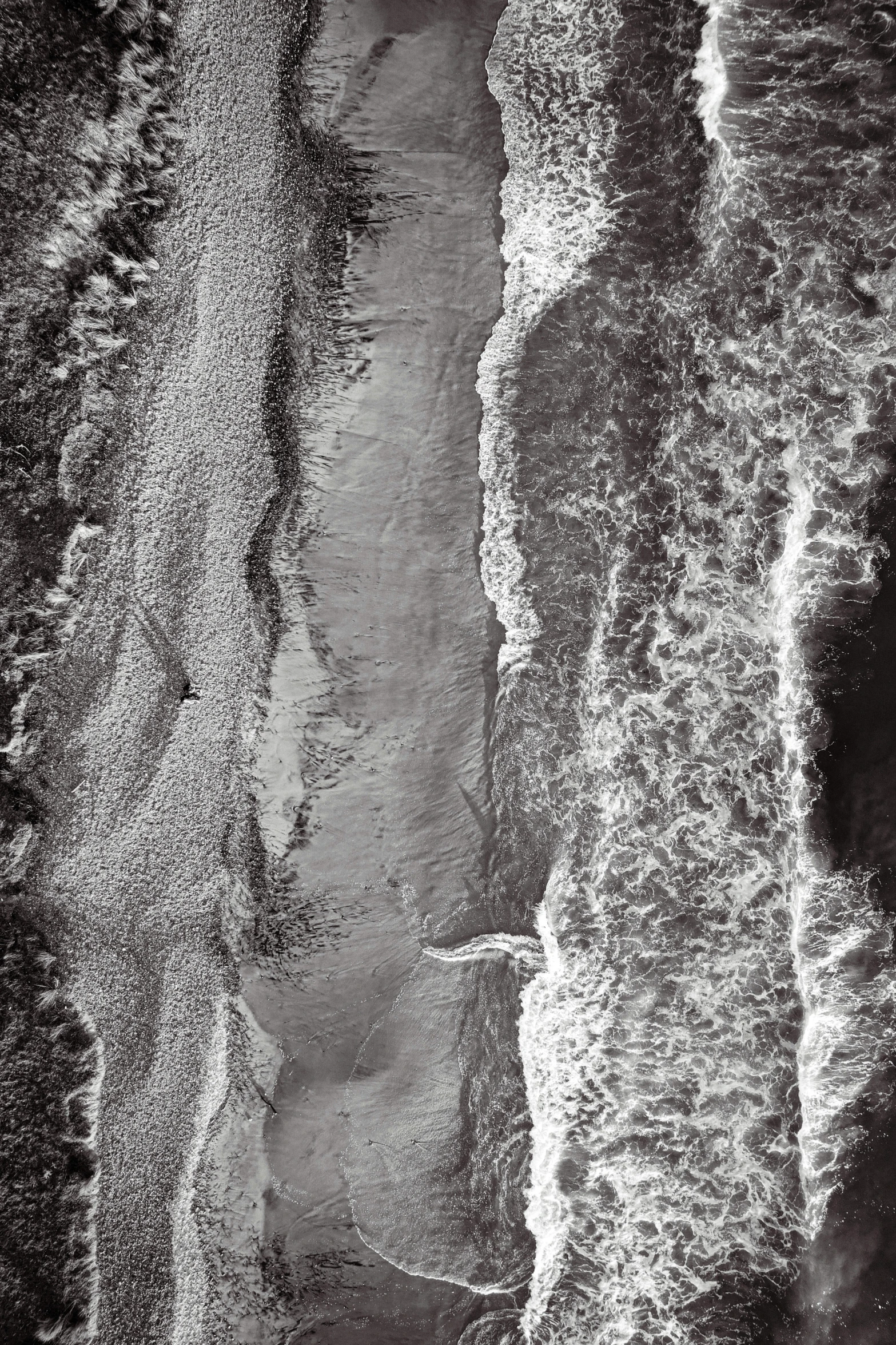 black and white po of sandy beach with waves coming up