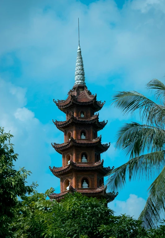 the top of a tall pagoda with a palm tree in front