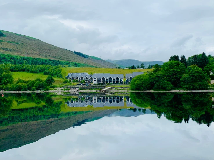 trees, mountains and water in the foreground with reflection on a cloudy day