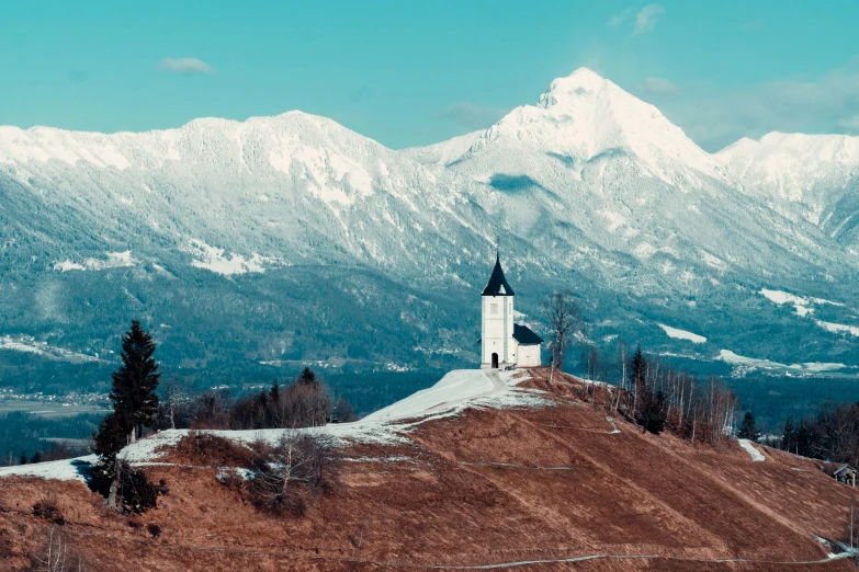 the church on the top of a hill in front of mountains