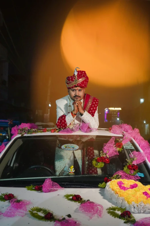 the man sitting on the back of the car is dressed in red and white