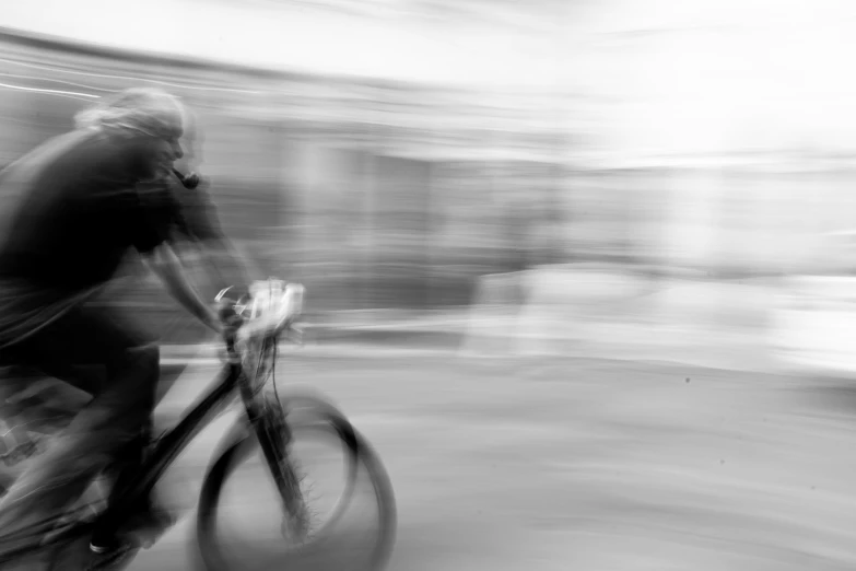 a bicyclist with his back turned is seen speeding down the road