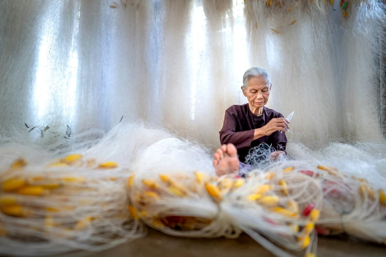 the woman is weaving several strands of white material