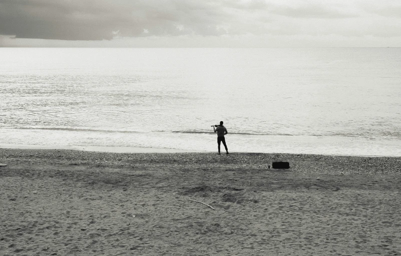 the person stands alone on a beach with no umbrella