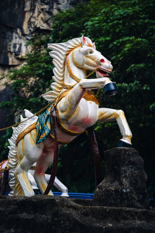 a horse statue with trees and rocks in the background