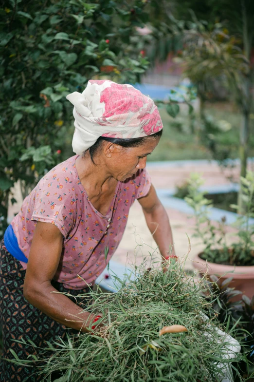 a woman working on a garden while wearing a scarf