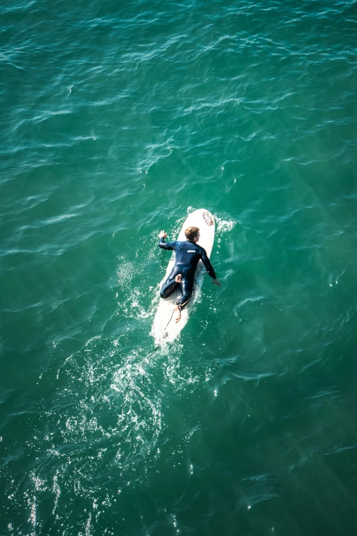 person sitting on surfboard paddling in the ocean