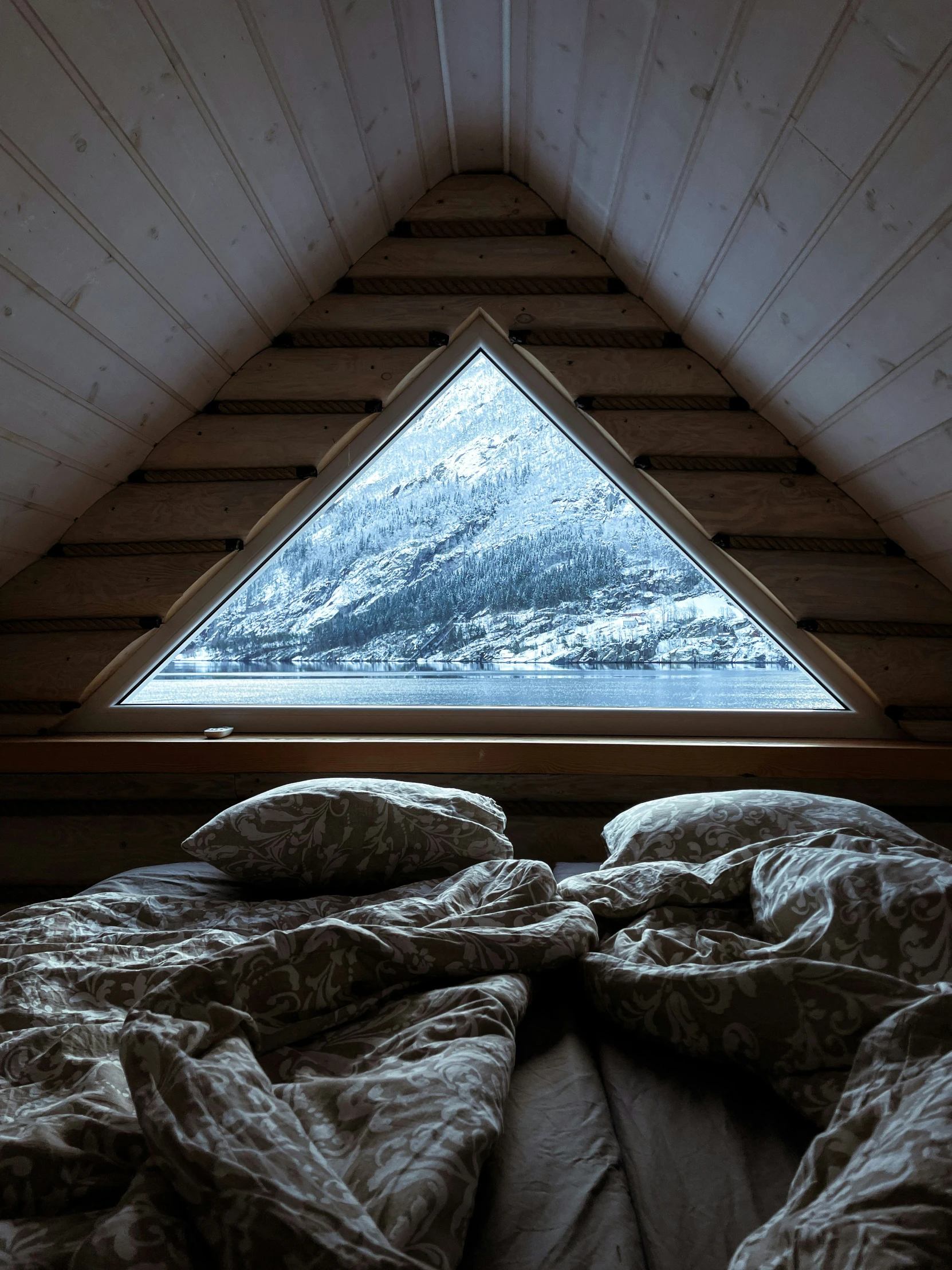 a bed with blankets on top of it in front of a window